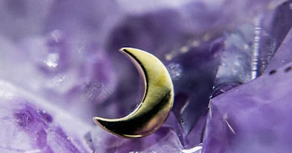 This image showcases a gold crescent moon stud, beautifully set against a purple amethyst crystal background, creating a celestial and mystical aesthetic. Key Features: Material: High-polish gold (or gold-plated finish). Design: Minimalist crescent moon shape. Vibe: Celestial-inspired jewelry perfect for: Helix Tragus Conch Flat piercings. The pairing of the luminous gold moon with the amethyst highlights its ethereal, dreamy quality — perfect for those who adore nature and celestial-inspired piercings.