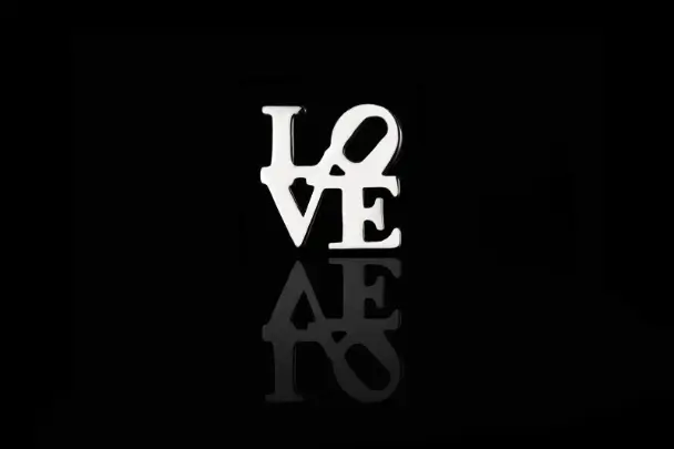 a silver love sign on a black background